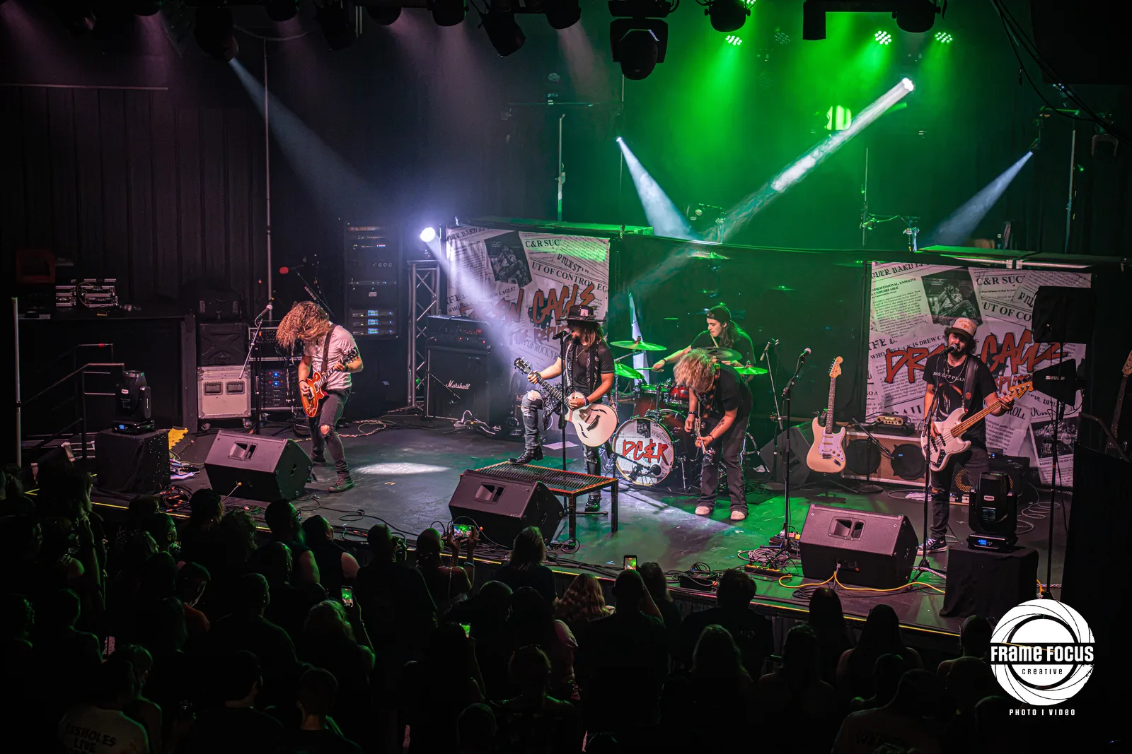 A band performing under stage lights to a full crowd at The City Center